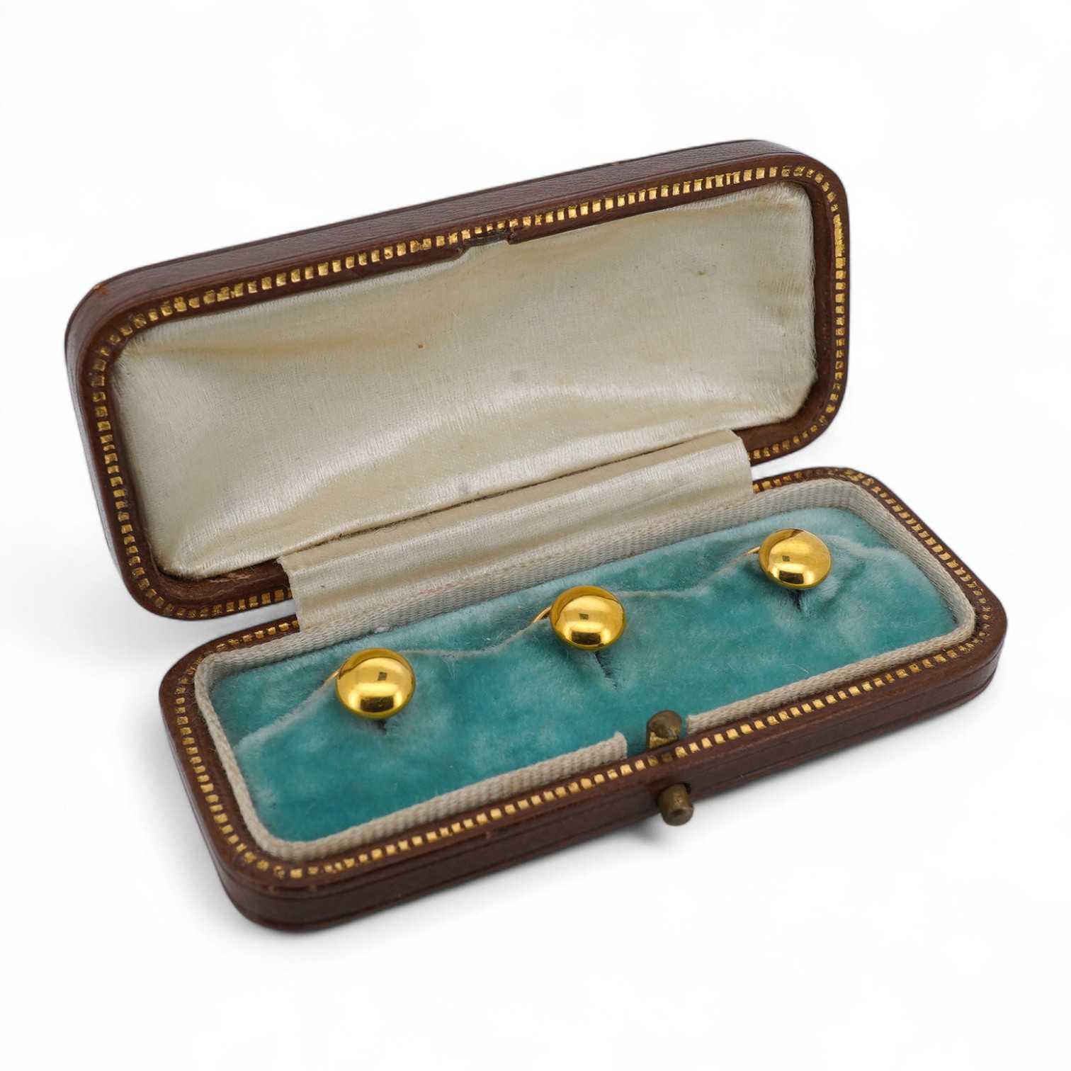 A set of three gold dress studs, each of circular outline in polished gold, approximately 7mm diameter each, each marked 18ct, combined gross weight 3 grams, fitted case